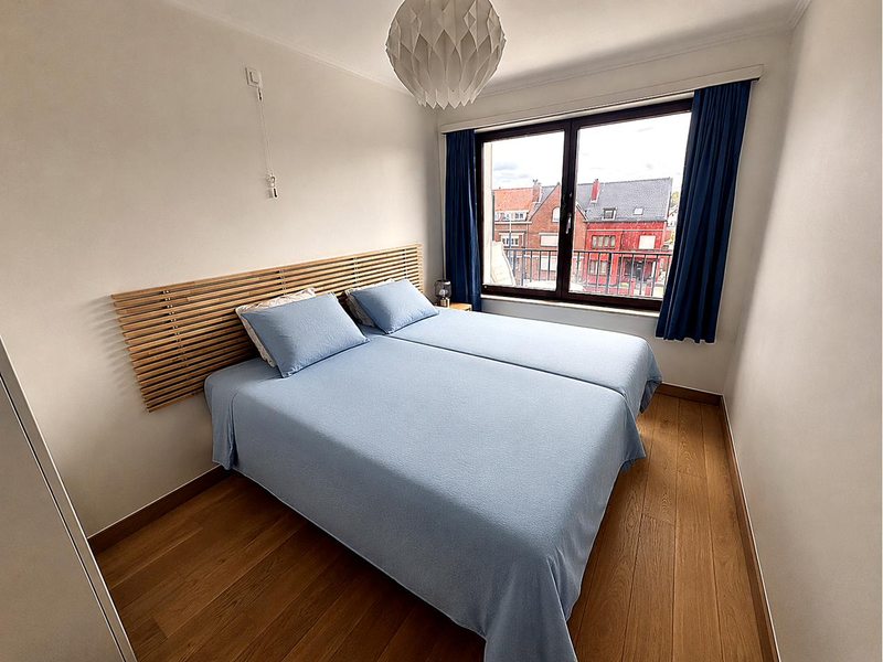 Chambre bleue de l'appartement avec lit double et vue sur Coxyde